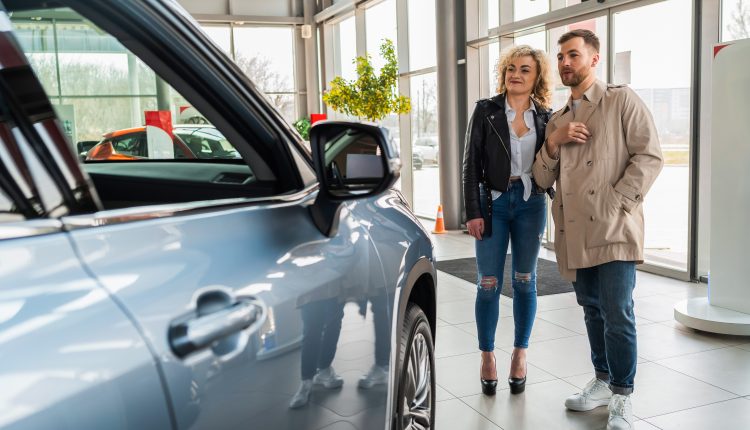 Beautiful couple in car dealership chooses car